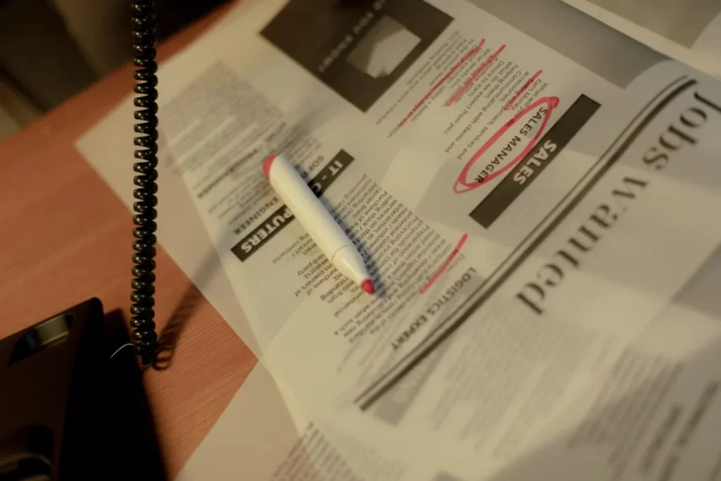 Newspaper job section with a red marker and a phone