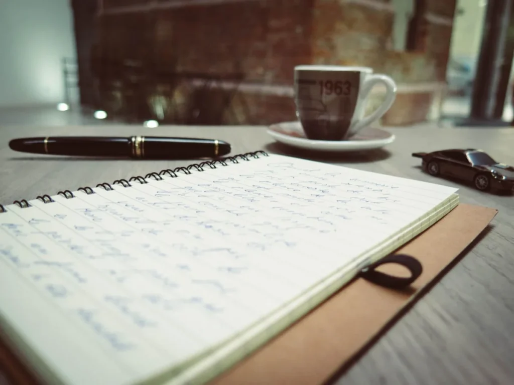 Workspace with coffee, handwritten notes and a pen