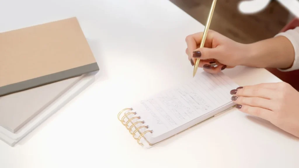 Hands writing in a spiral notebook