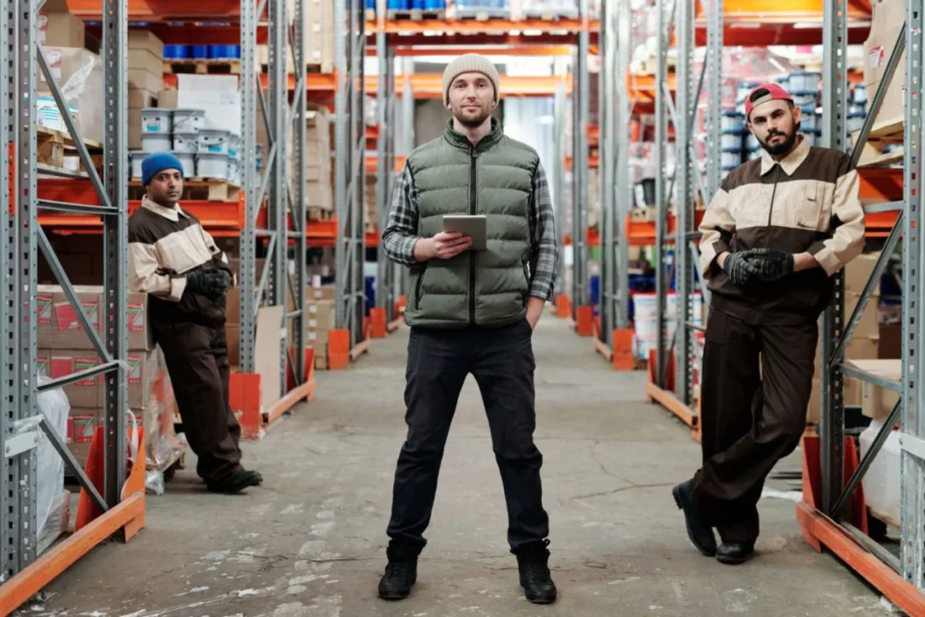 Three warehouse workers standing among inventory shelves