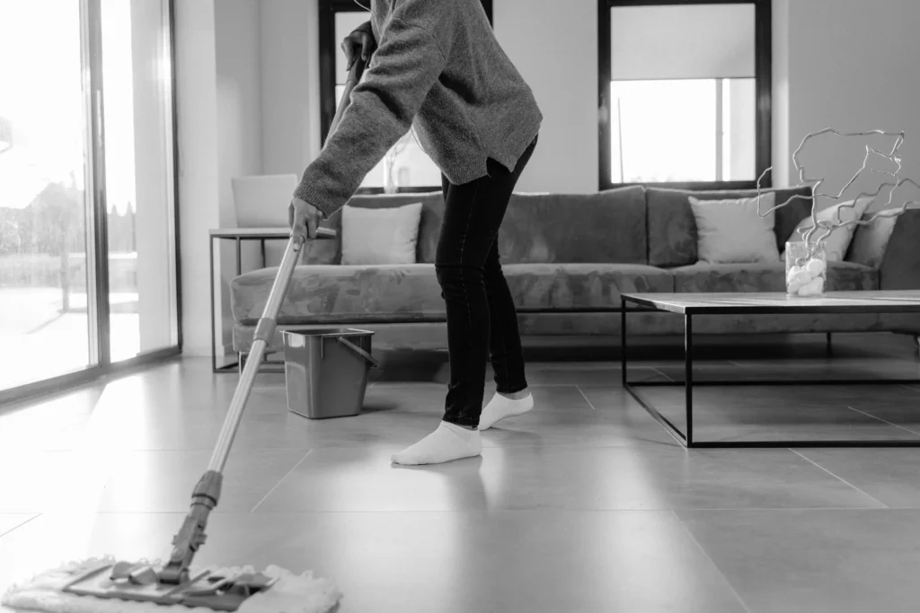 A grayscale photo of a person mopping the floor in a modern living room