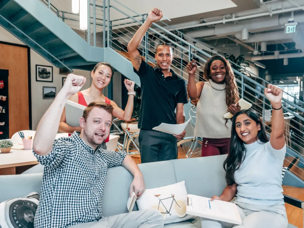 A diverse group of coworkers cheerfully celebrating success in a modern office setting