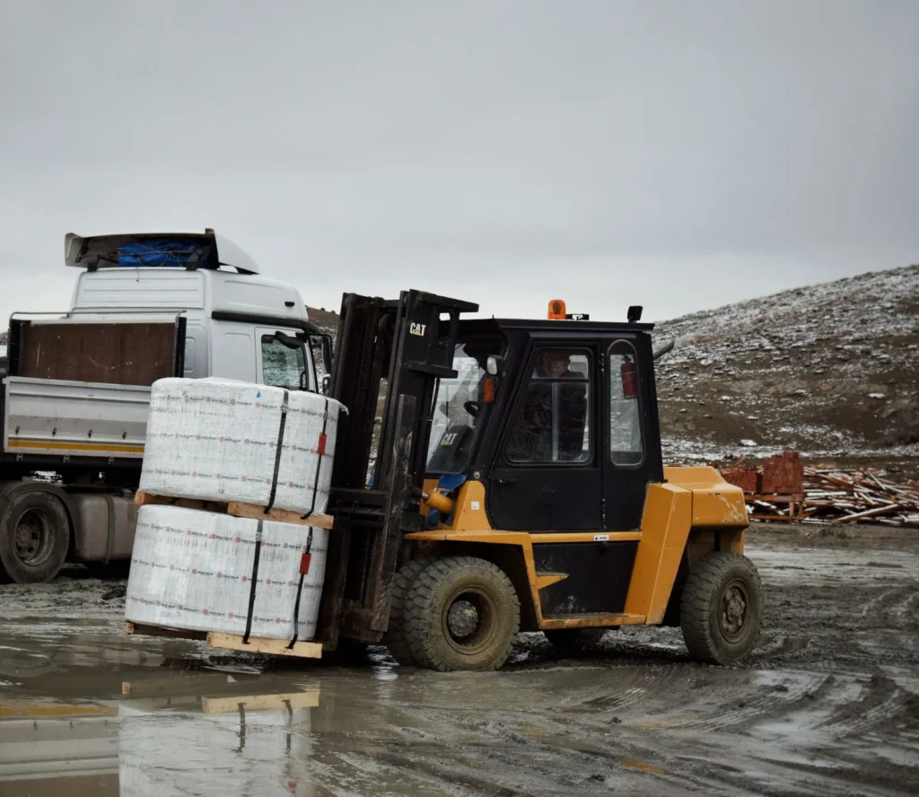Forklift transporting large pallet in an outdoor industrial setting