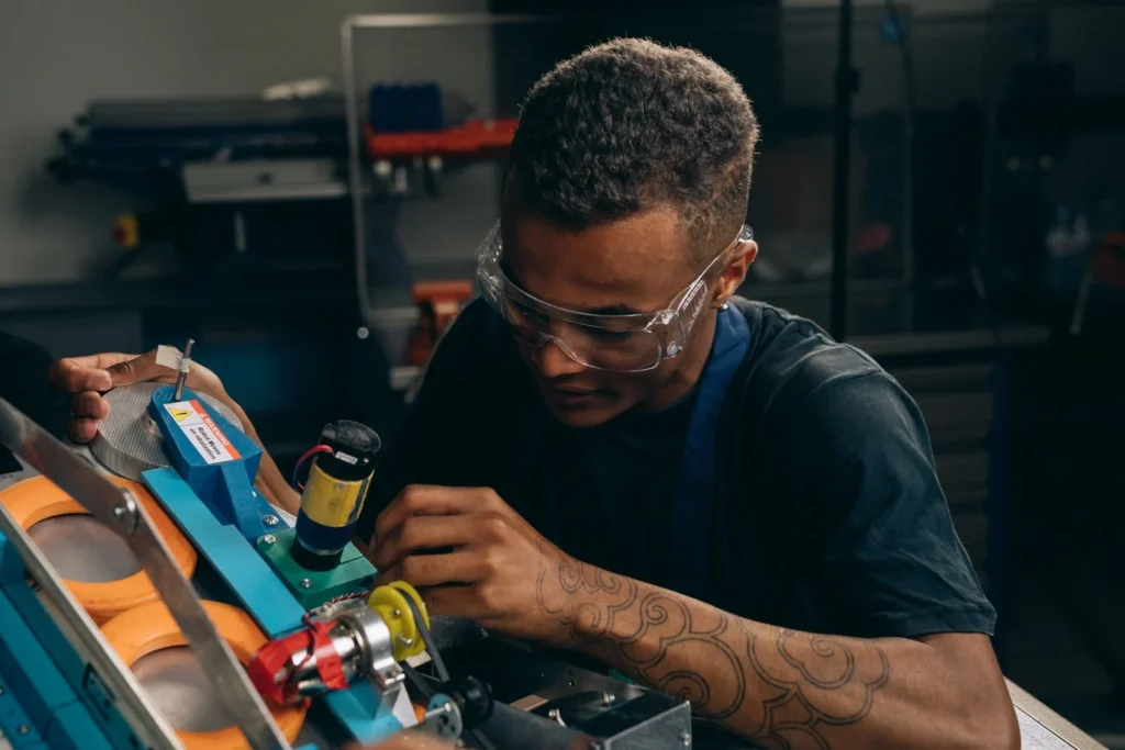 Worker in safety glasses adjusting machinery, a common task in light industrial jobs