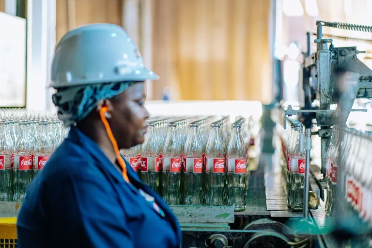 Light industrial jobs worker in a hard hat checking bottles on an assembly line