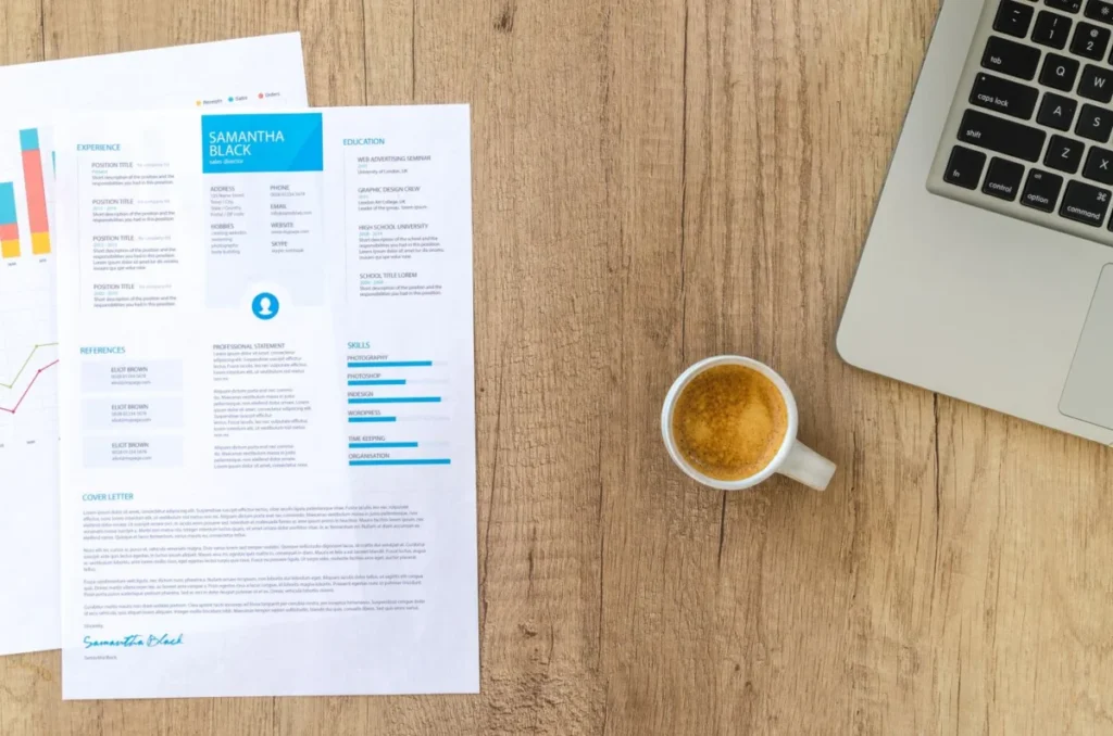 Resume, coffee and laptop on a desk while applying for temp jobs