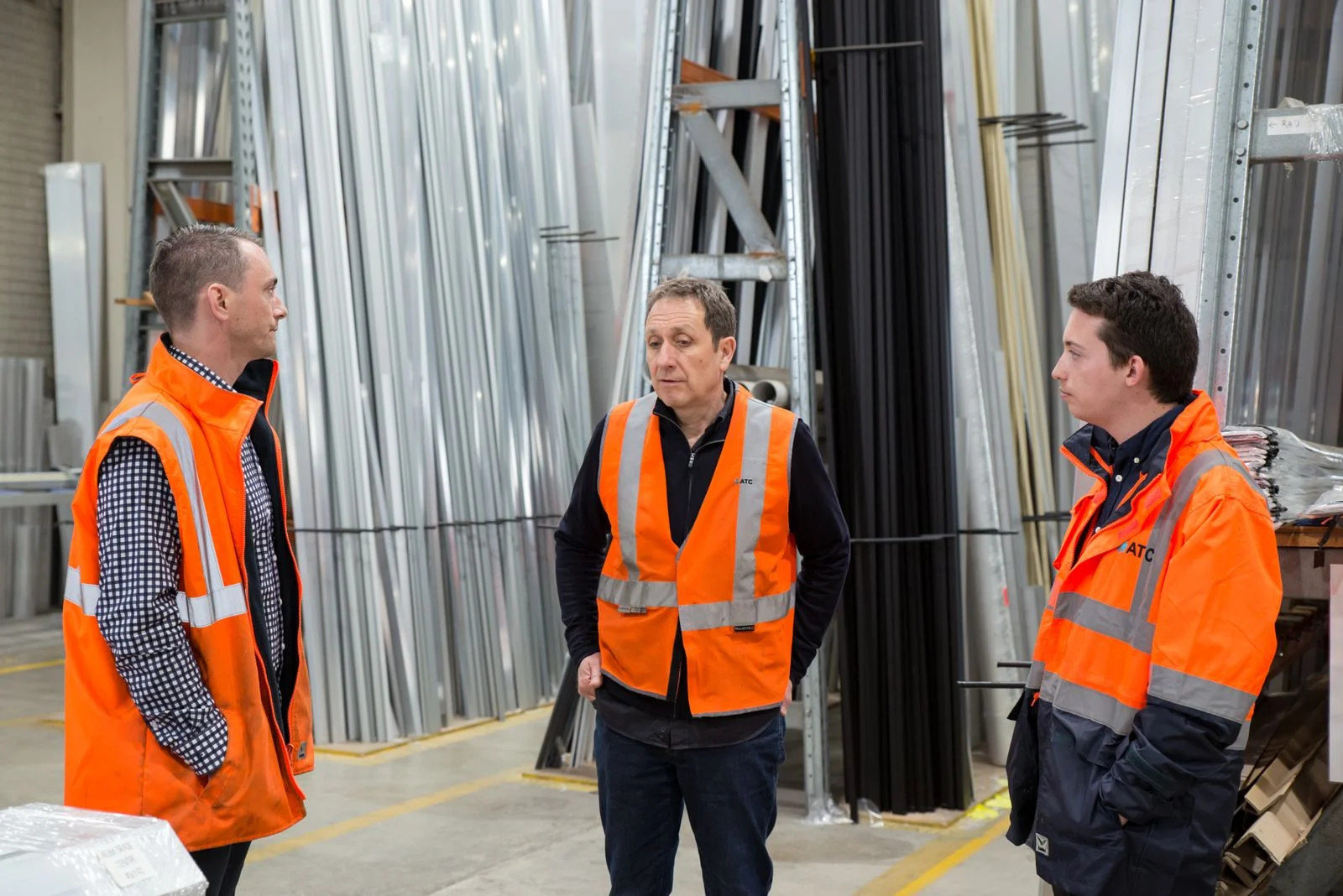 Temporary staffing team in high-visibility vests talking in a warehouse